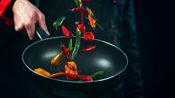 Super Slow Motion Shot of Chef Holding Frying Pan and Falling Chilli Peppers at 1000Fps.