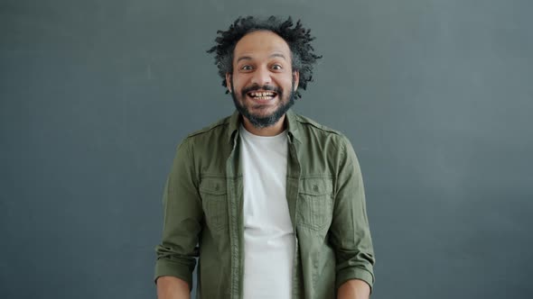 Portrait of Crazy Mixed Race Guy Clapping Hands and Looking at Camera with Funny Face