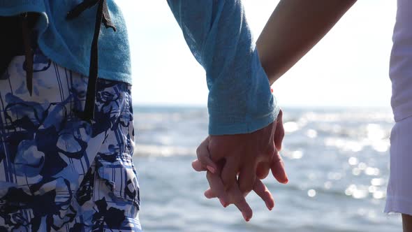 Young Pair of Lovers Holding Hands and Flirting to Each Other Standing on Ocean Coast