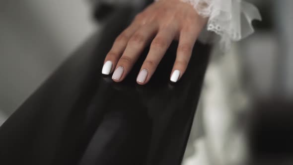 Manicured Hand of Bride in Wedding Dress Touches Railing