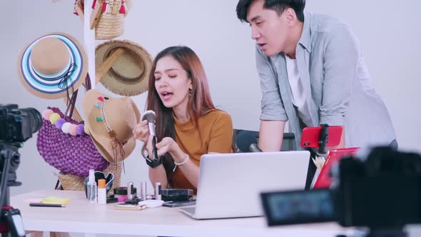 Young Asian couple bloggers are reviewing cosmetic product online by live streaming.