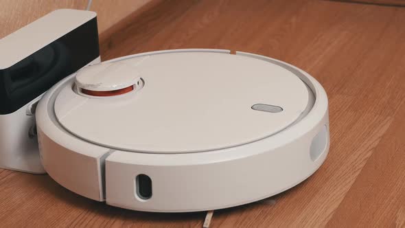 White Robotic Vacuum Cleaner Starts Cleaning From Its Charging Station