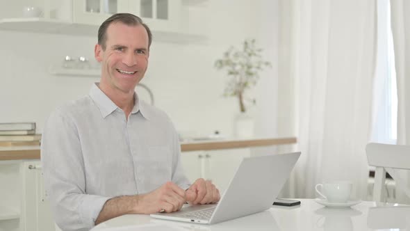 Middle Aged Man with Laptop Smiling at the Camera