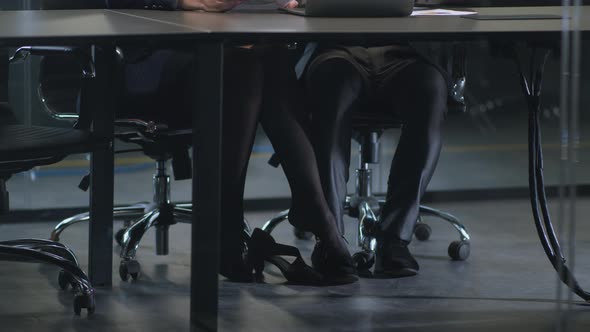 Lady Boss Sexually Harassing Her Young Man Subordinate Touching His Leg with Foot Under Table at