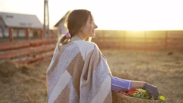 Rear View of a Woman with Basket Carrying Fresh Vegetables or Plants Just Picked in the Morning