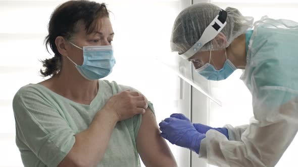 Doctor or Nurse Injects the COVID19 Vaccine Into an Elderly Female Patient's Shoulder