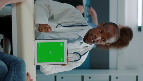 Vertical Video Tripod Shot of Doctor Using Green Screen Background on Tablet