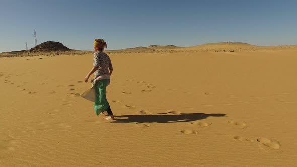 Happy woman running barefoot in desert, Egypt