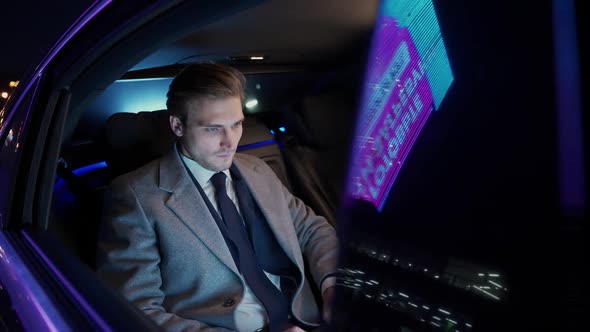 Businessman Sitting in a Car and Using Laptop Top Manager in a Suit is Sitting in the Back of a