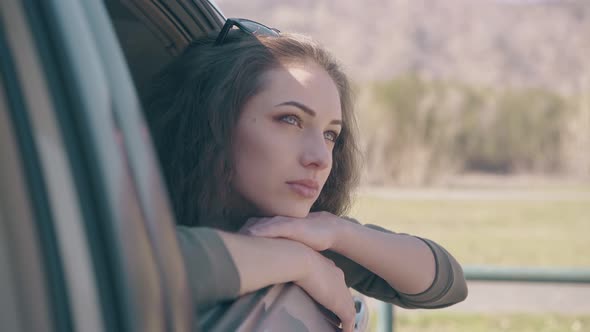 Calm Young Woman with Blue Eyes Leans Out of Car Window