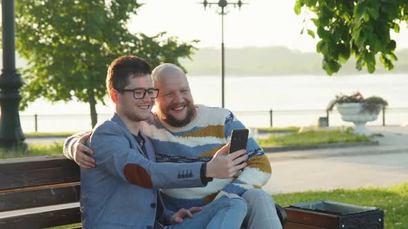 Cute Male Homosexual Gay Couple Spend Time Together in Park. Men Taking Selfie on Smartphone Dating