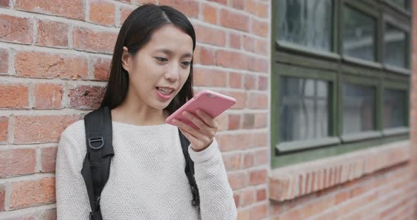 Woman use of smart phone over red brick wall