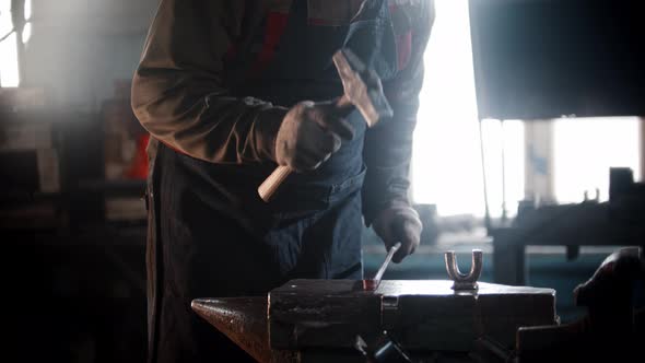 Blacksmith Workshop  a Man Blacksmith Bends a Piece of Metal with Hitting It with a Hammer