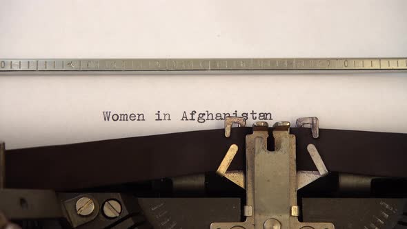 Typing phrase Women in Afghanistan on retro typewriter. Close up.