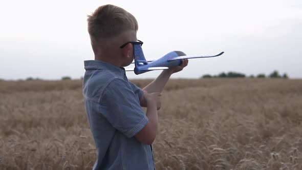 Happy guy with a toy airplane on a wheat field in the sunset light.