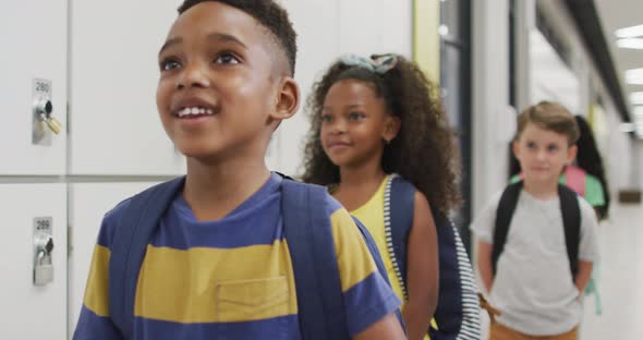 Video of happy diverse pupils standing in row and smiling before entering classroom