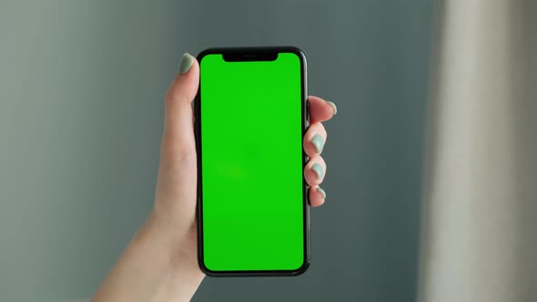 Woman hand using smart phone, touches the green screen. Green Mock-up