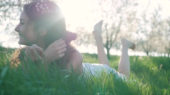 Beauty Smiling Girl lying on the Spring Meadow with wild Flowers. Laughing And Happy. Enjoy Nature.
