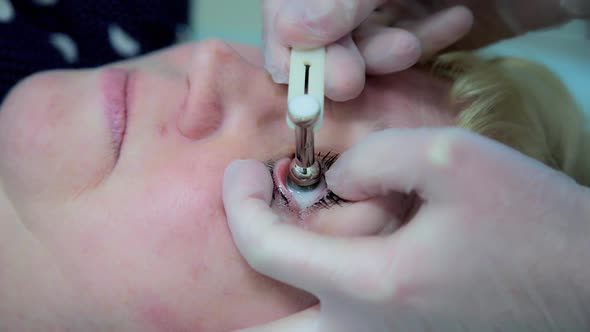 An ophthalmologist checks the eye pressure of an adult woman using a special device before a treatme