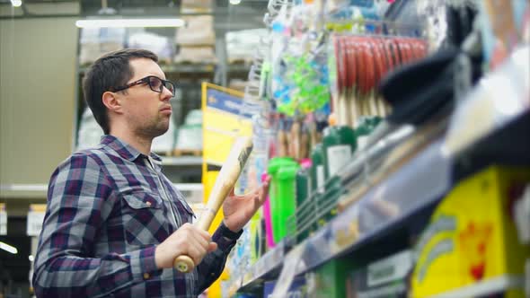 A Man in Glasses Selects a Baseball Bat for a Teenager in a Sporty Store