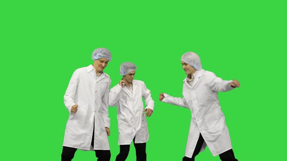 Three Male Doctors in White Robes and Protective Caps Running in the Frame and Start Dancing in a