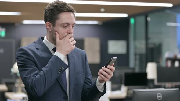 Upset Businessman Reacting to Loss on Smartphone