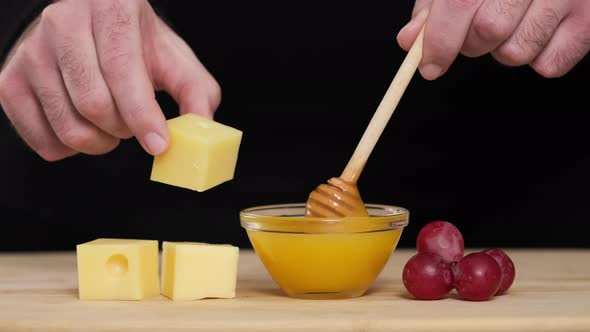 Man tasting cheese with honey and grapes