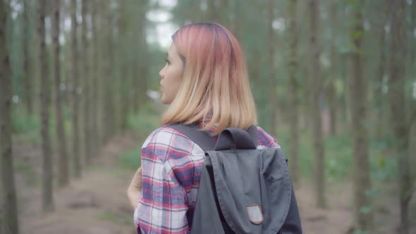 Hiker Asian backpacker woman adventure feeling freedom walking in forest holidays near lots of tree.