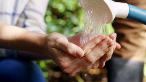 Couple watering plant in garden