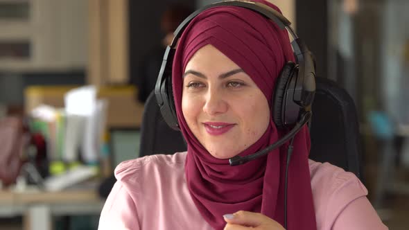 Beautiful modern muslim business woman uses a microphone and headphones in office