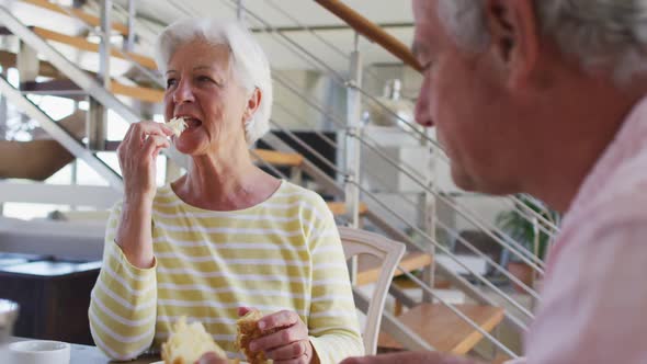 Senior caucasian couple having breakfast together talking to each other at home