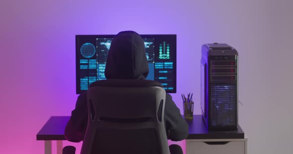 Rear View of Man Programmer Happy with Success While Working at a Computer in Data Center at Night