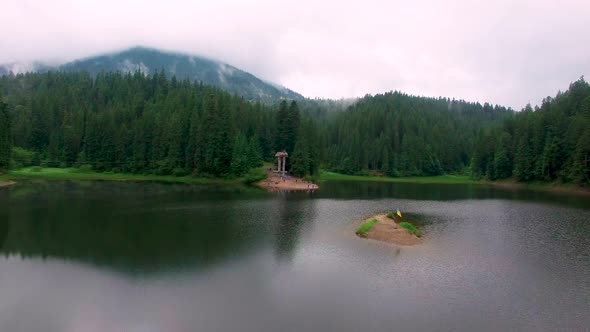 Aerial drone flight over mountain lake in pine forest