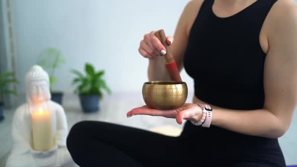woman practicing yoga and meditation with singing bowl sitting on floor