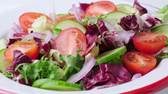 Olive oil pouring onto fresh vegetable salad