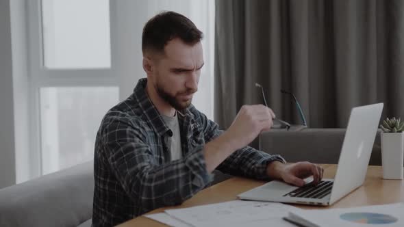 Upset Man Massaging Nose Bridge Taking Off Glasses Feeling Eye Strain After Long Work with Laptop