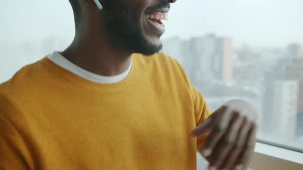 Joyful African American Man Dancing Listening to Music Through Earphones and Using Smartphone at