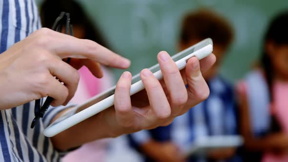 Teacher standing holding digital tablet