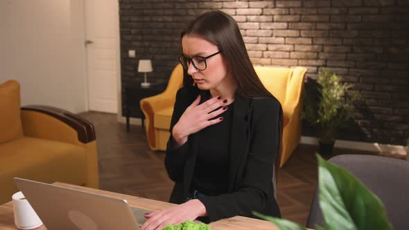 Pretty Caucasian Businesswoman in Glasses Coughing Work on a Laptop at Home or Office