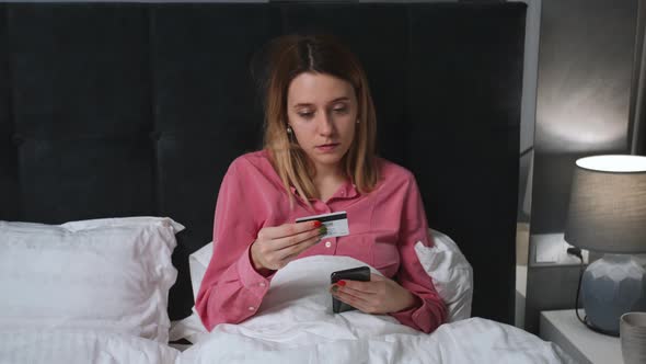 Woman Doing Online Shopping Using Phone and Credit Card While Laying on Bed