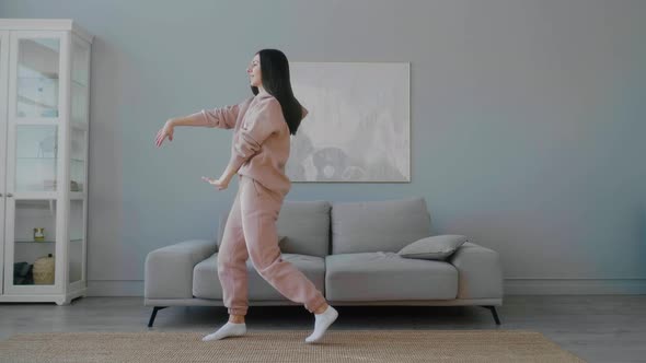 A young Caucasian woman with glasses having fun, dancing, making funny movements and waving hands.