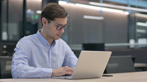 Young Man Working on Laptop in Office
