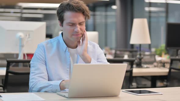 Man Having Toothache While Working on Laptop in Office