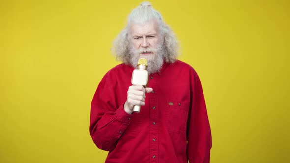 Concentrated Senior Bearded Man Singing Romantic Song on Yellow Background