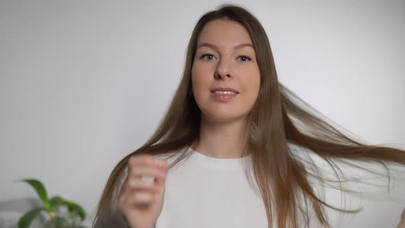 Young Woman Brushes Her Hair with a Comb