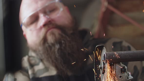 Male Craftsman Cuts Small Piece From Metal Pipe Using an Angle Grinder and Cutting Disc