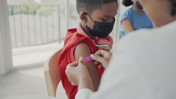 African american doctor is applying plaster to a child's shoulder after being vaccinated.