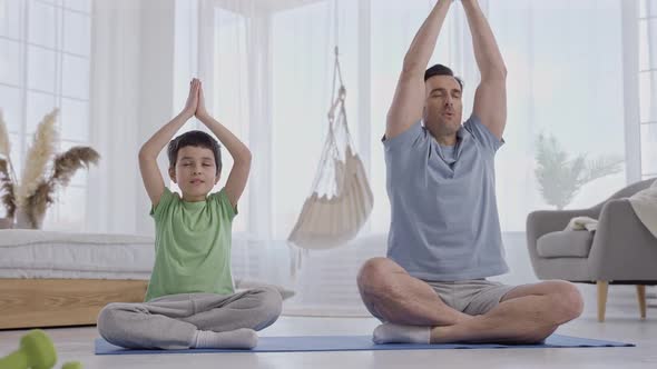 Father and Son Practicing Yoga in Living Room