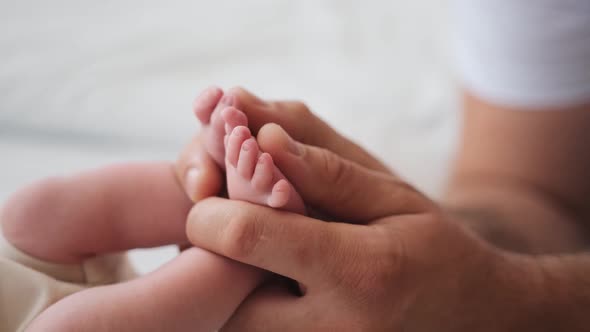 Father Holding Feet of Newborn Baby