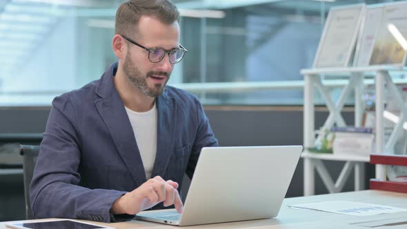 Middle Aged Businessman Celebrating Success While Using Laptop in Office